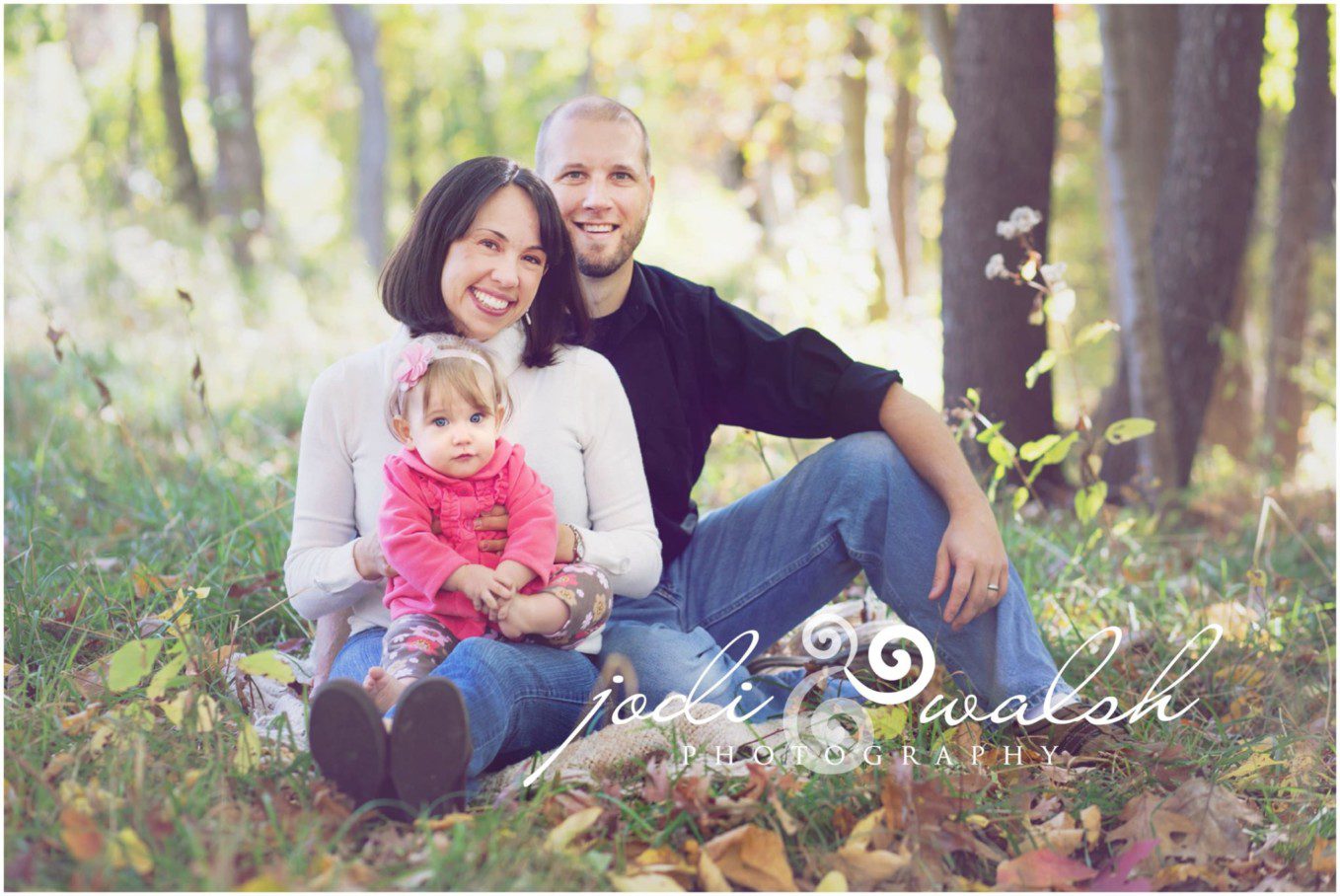 mom, dad, and baby girl sitting in the leaves