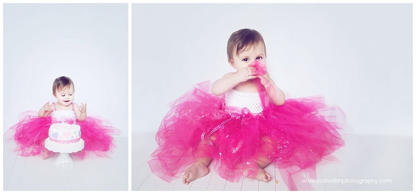 image of a baby girl wearing a pink tutu enjoying her first birthday cake smash session at home