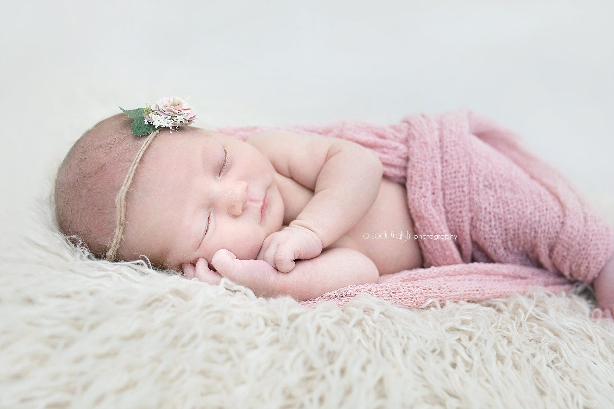 baby girl posed newborn session with pink wrap and tie back