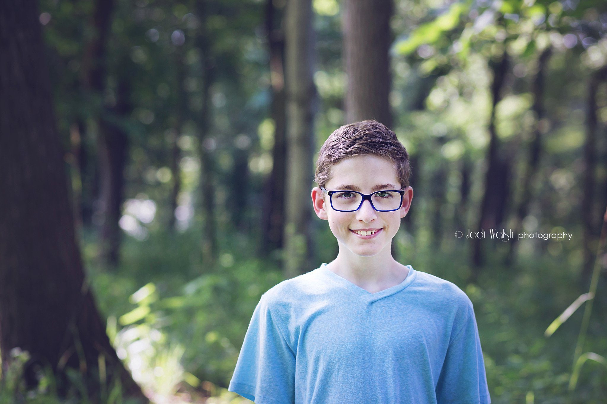 tween boy in woods with blue shirt and blue framed glasses