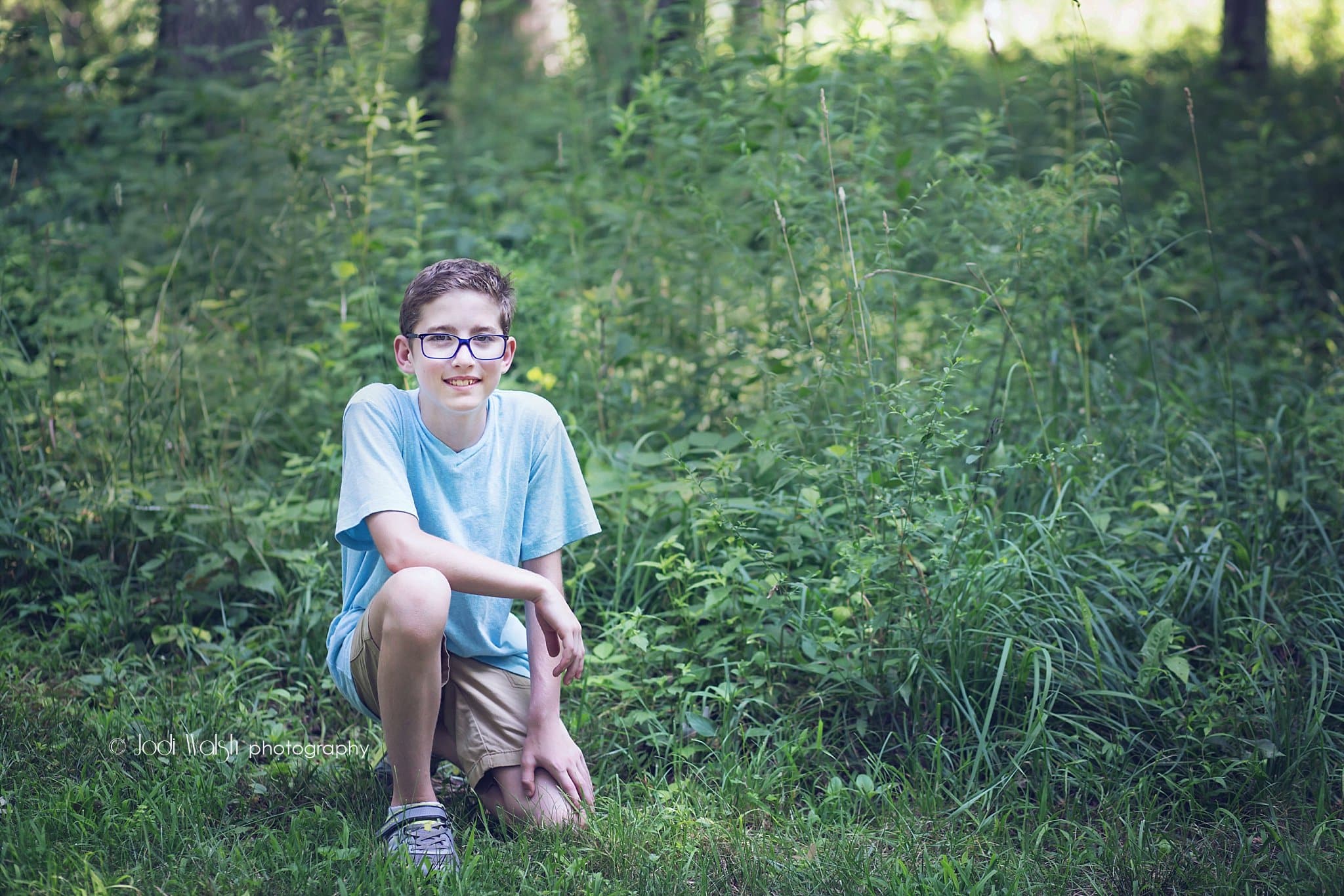 tween boy portrait in woods with blue shirt and blue framed glasses