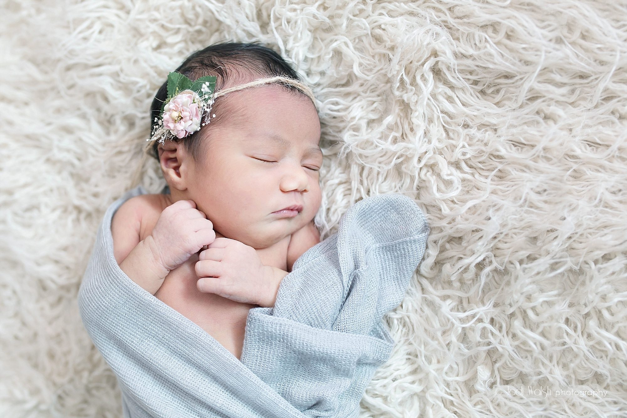 newborn baby girl with pink flower headband and light gray wrap
