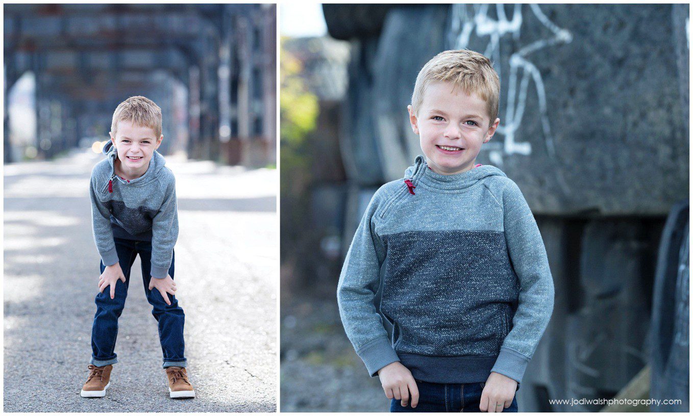 images of a little boy in the strip district.  He's wearing a two tone gray sweater and standing under a railroad bridge.