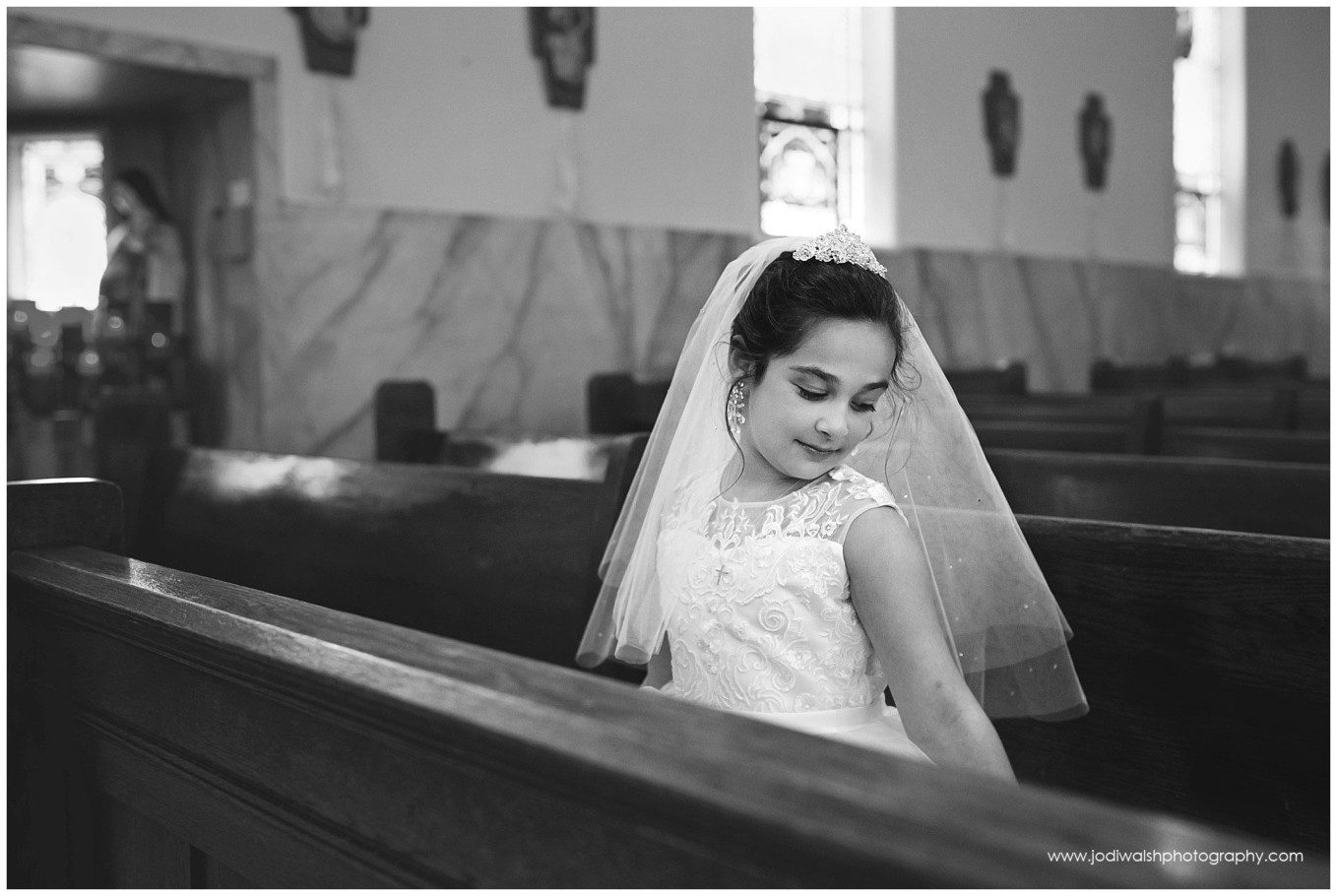 image of a little girl in white dress and veil sitting in church pew looking down