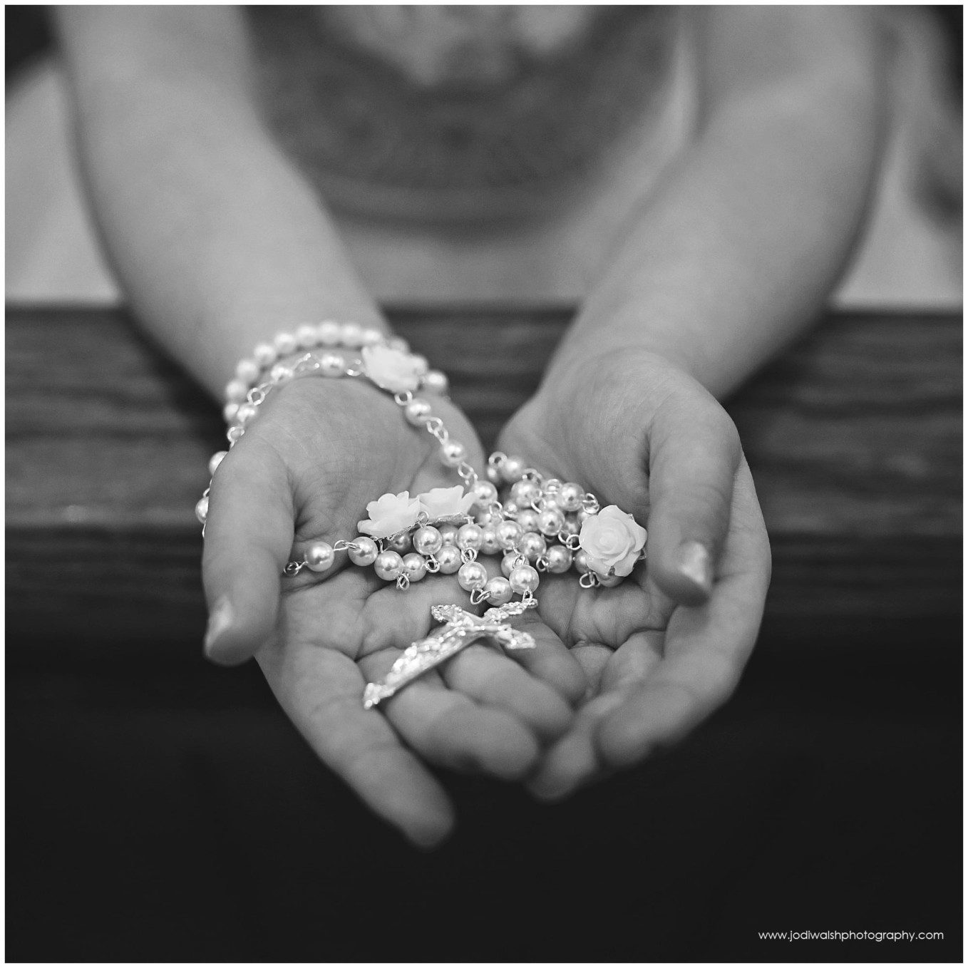 black and white image of white rosary beads in a little girl's hands
