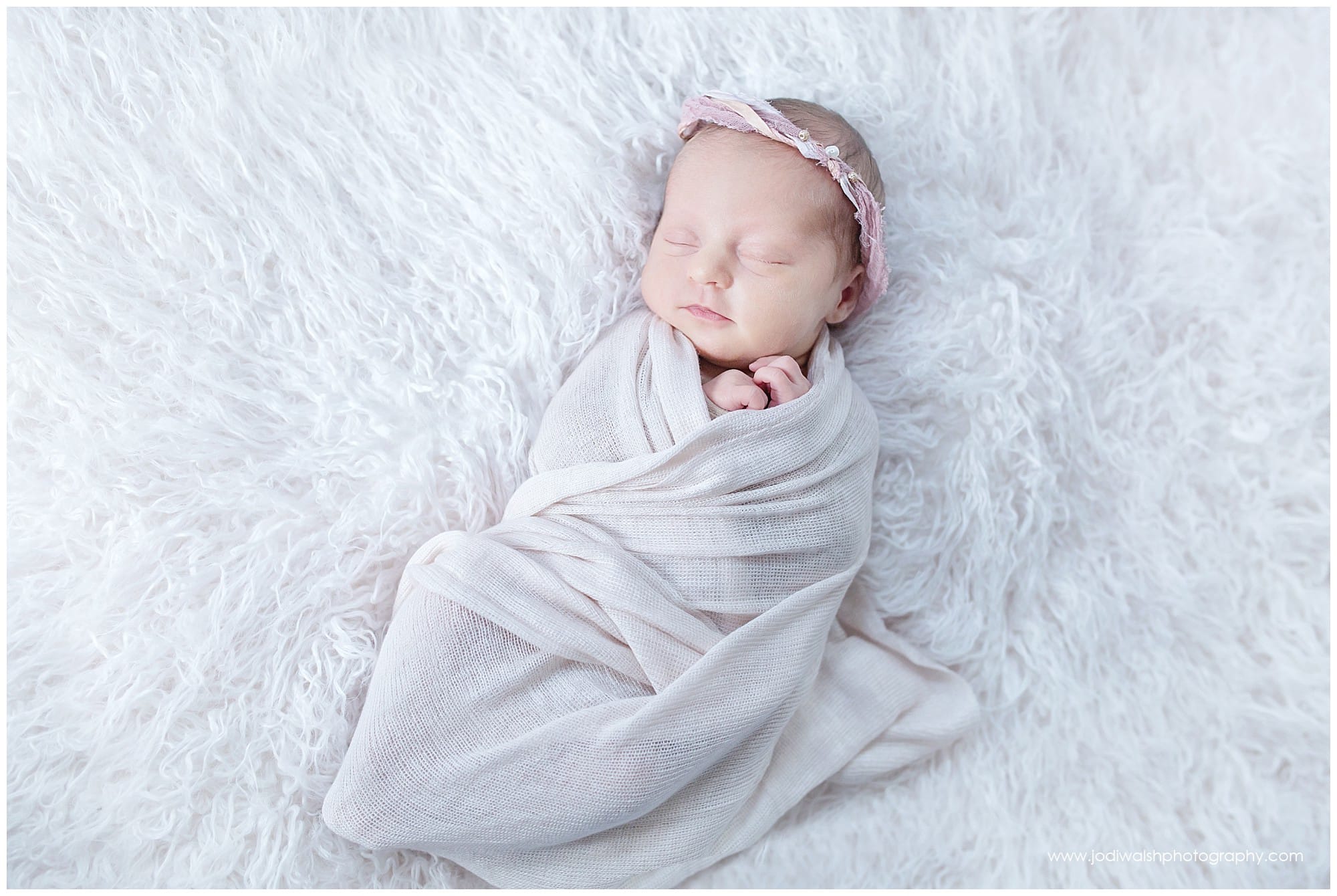 sleeping newborn baby girl with pale pink wrap and pink tie back