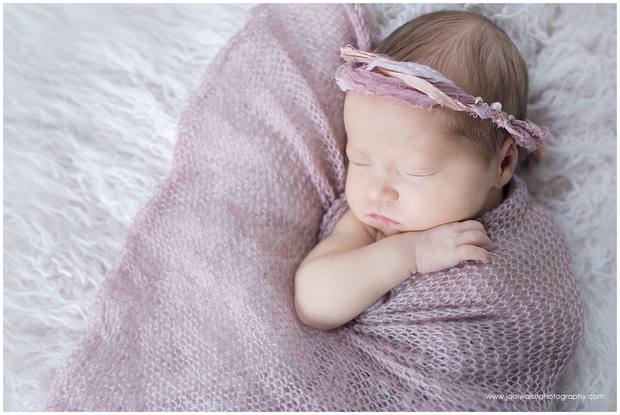 sleeping newborn baby girl with pink wrap and pink tie back