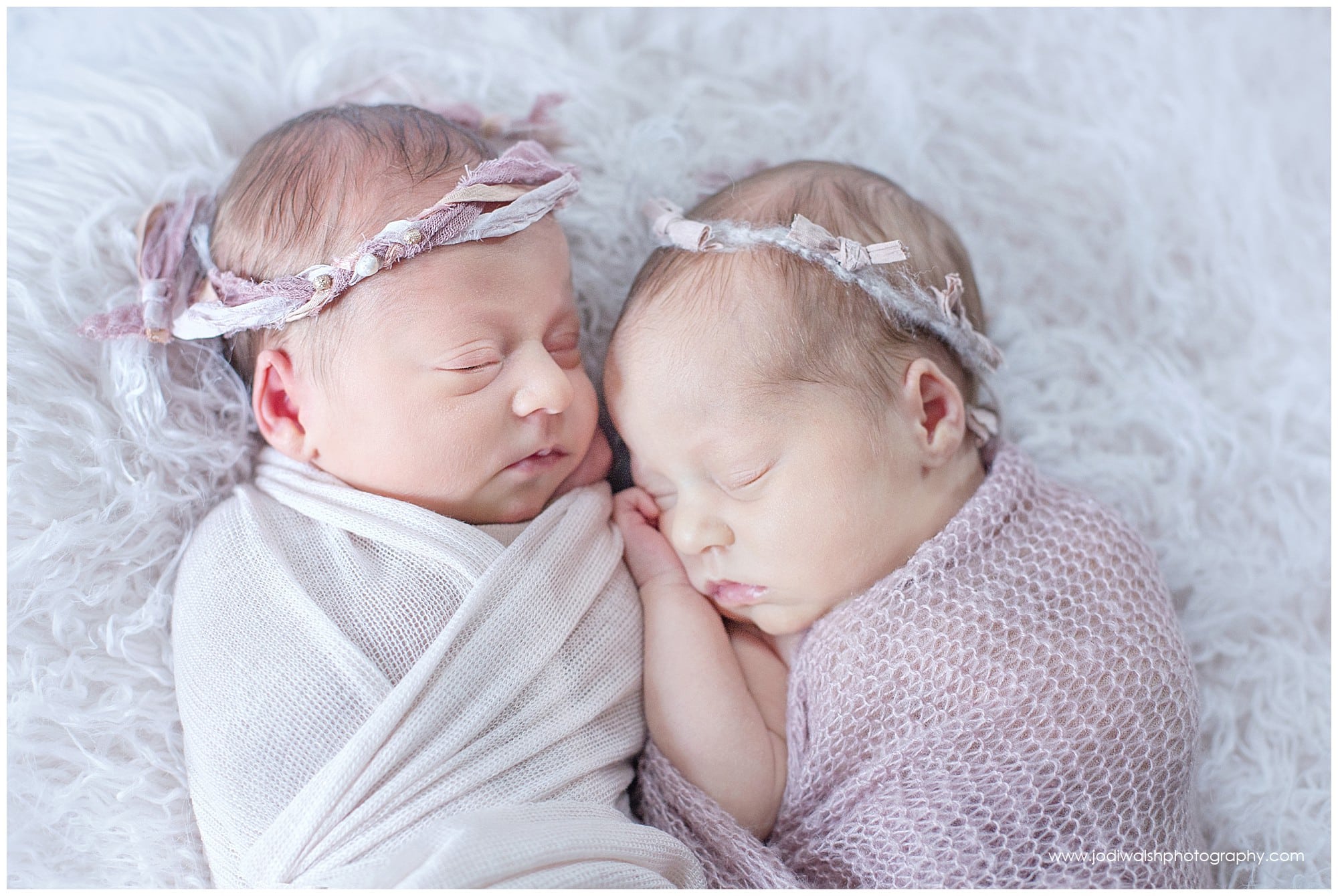 newborn twin girls with pale pink wraps and headbands