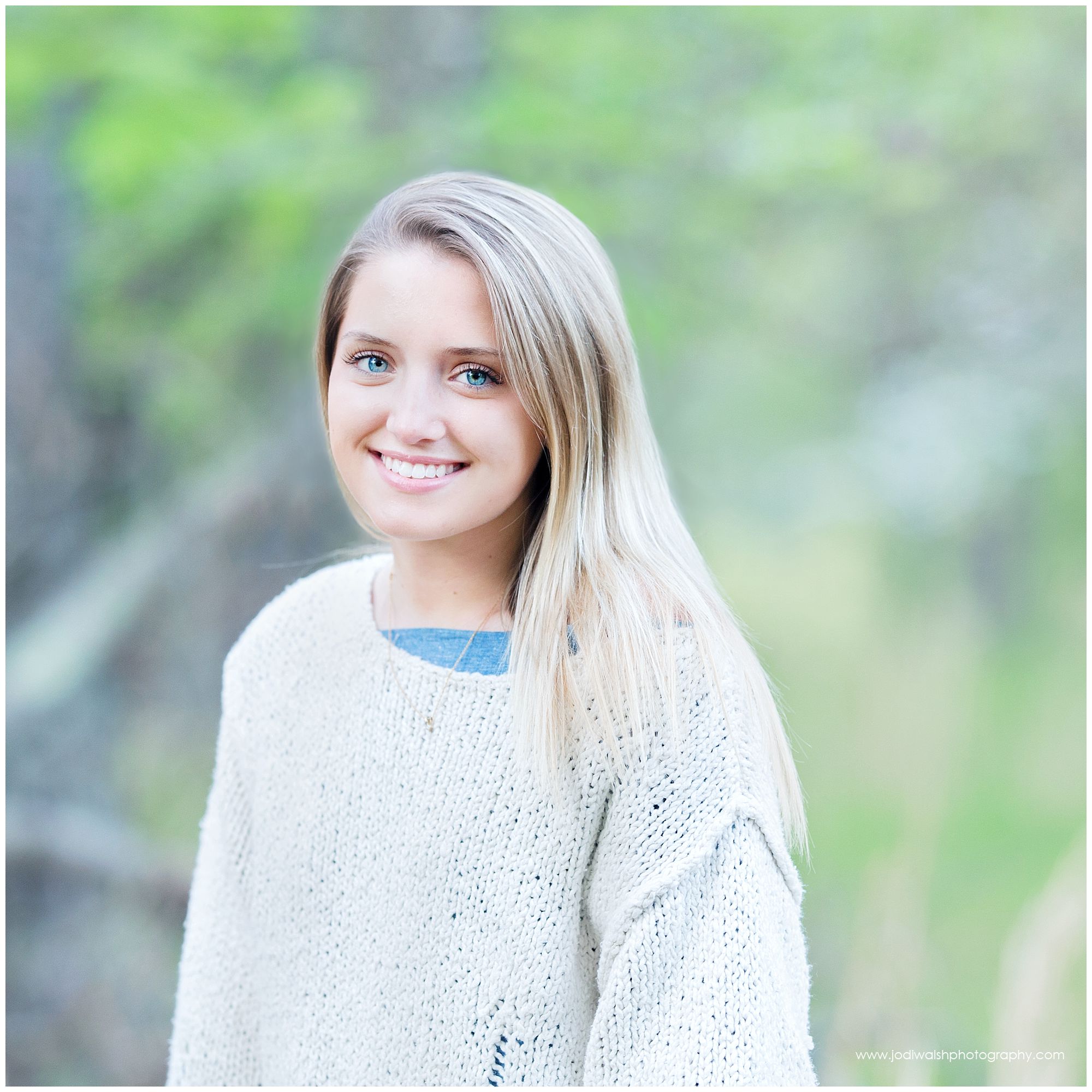 senior girl in cream sweater standing in tall grasses