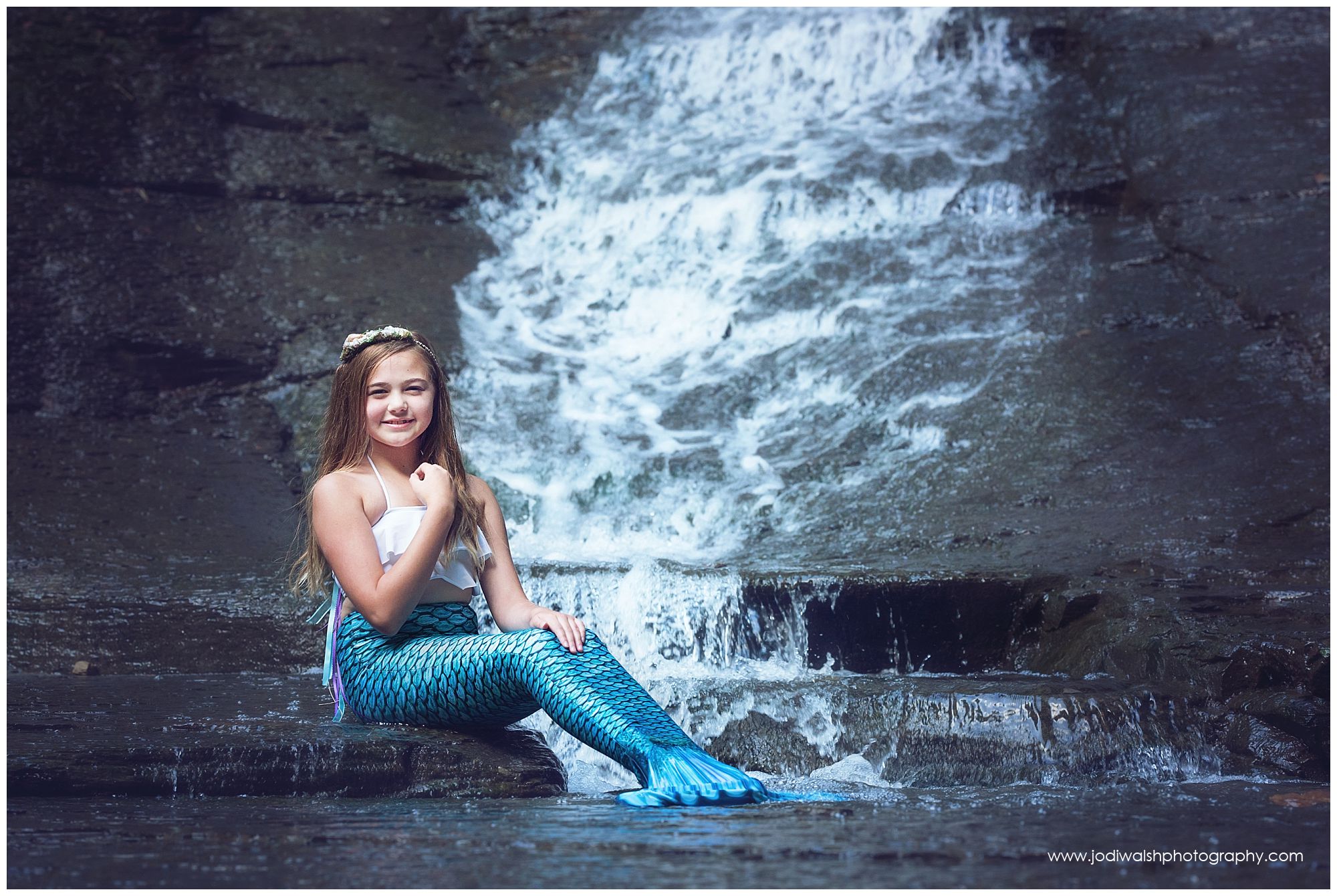 little girl in mermaid costume at waterfall