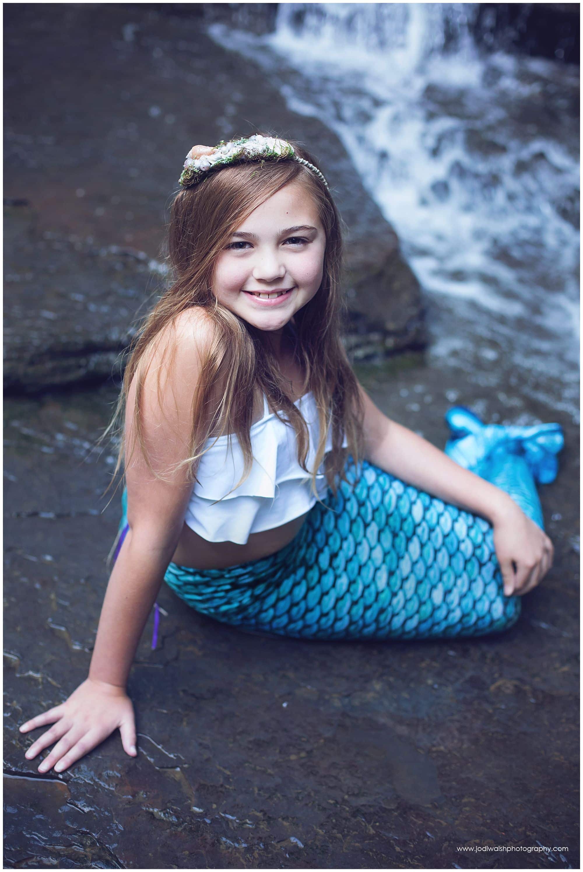 little girl in mermaid costume at waterfall