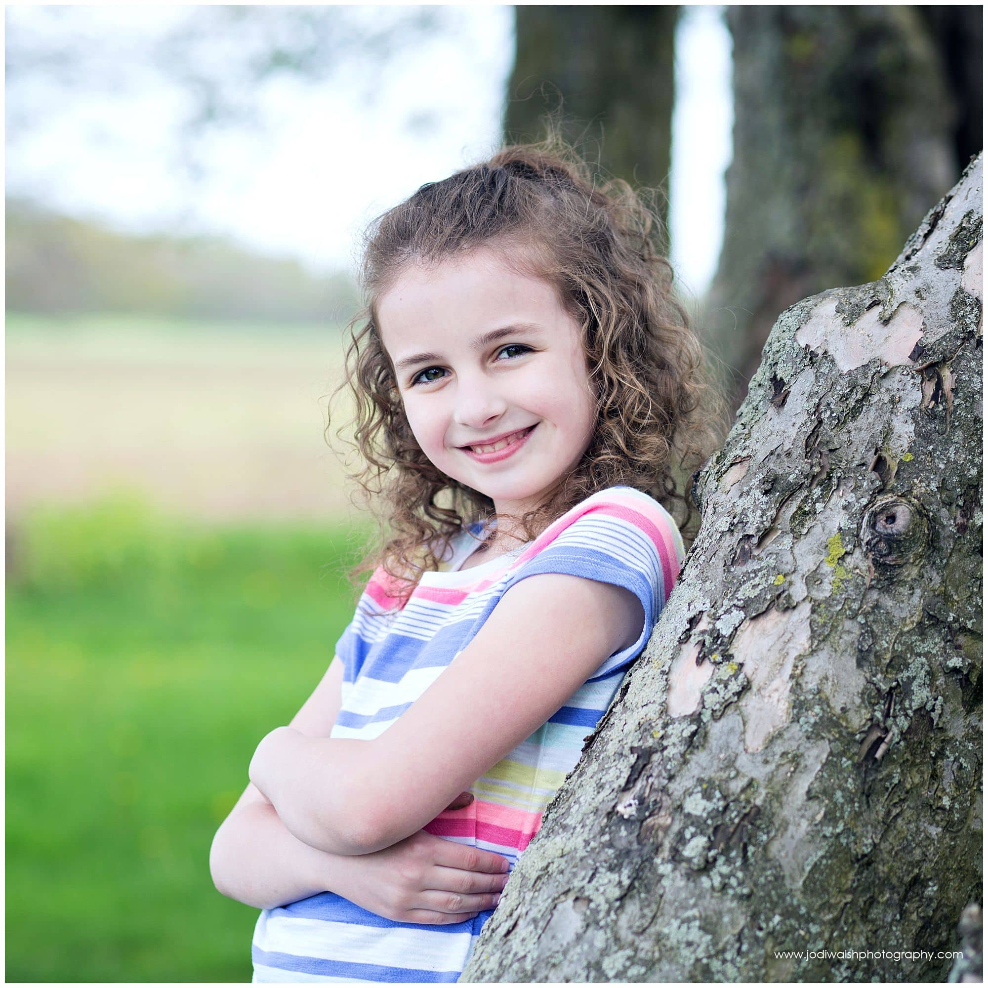 curly haired girl leaning against tree