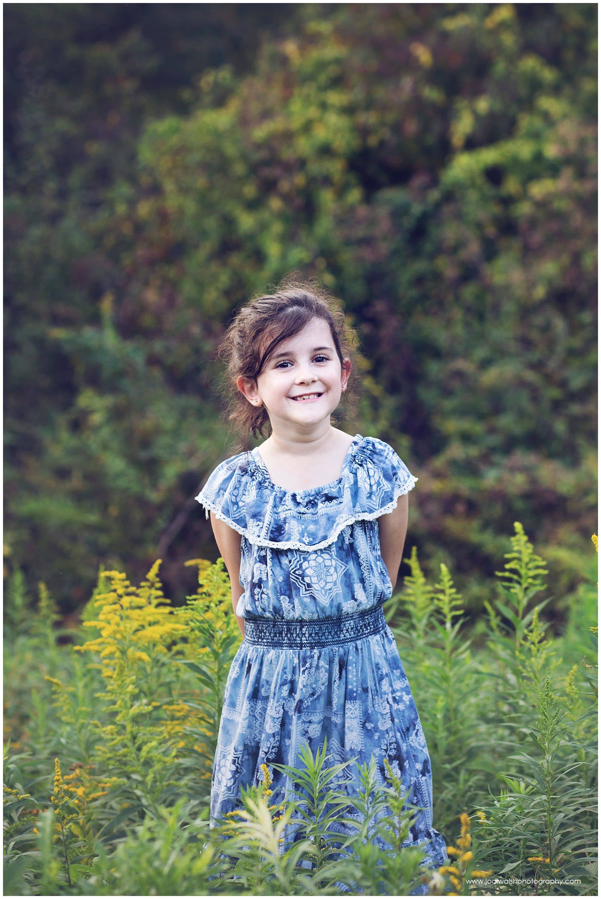 little girl in blue flower dress grinning in a field of tall grasses near Pittsburgh