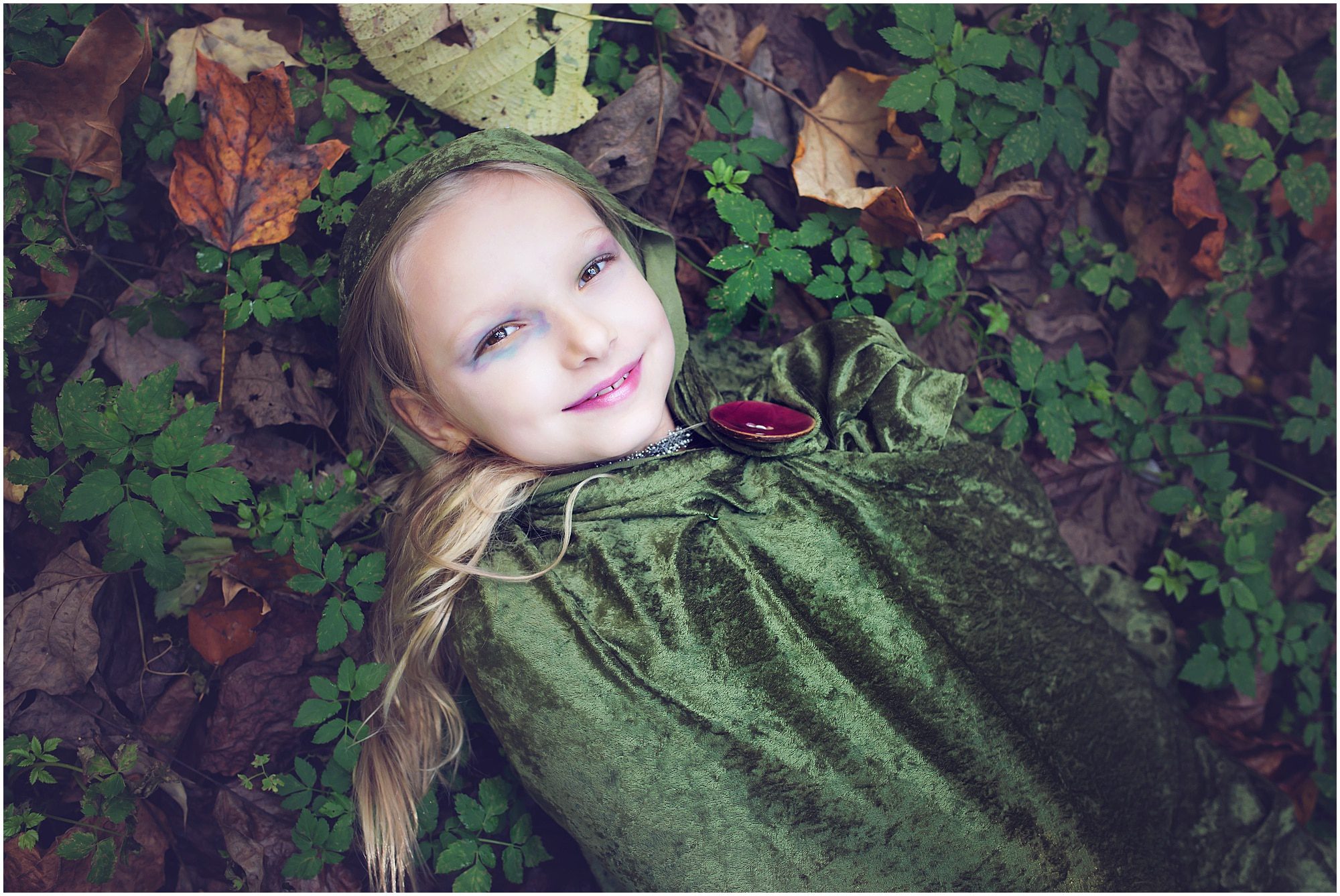 little girl laying in the leaves wearing green velvet cape, Pittsburgh