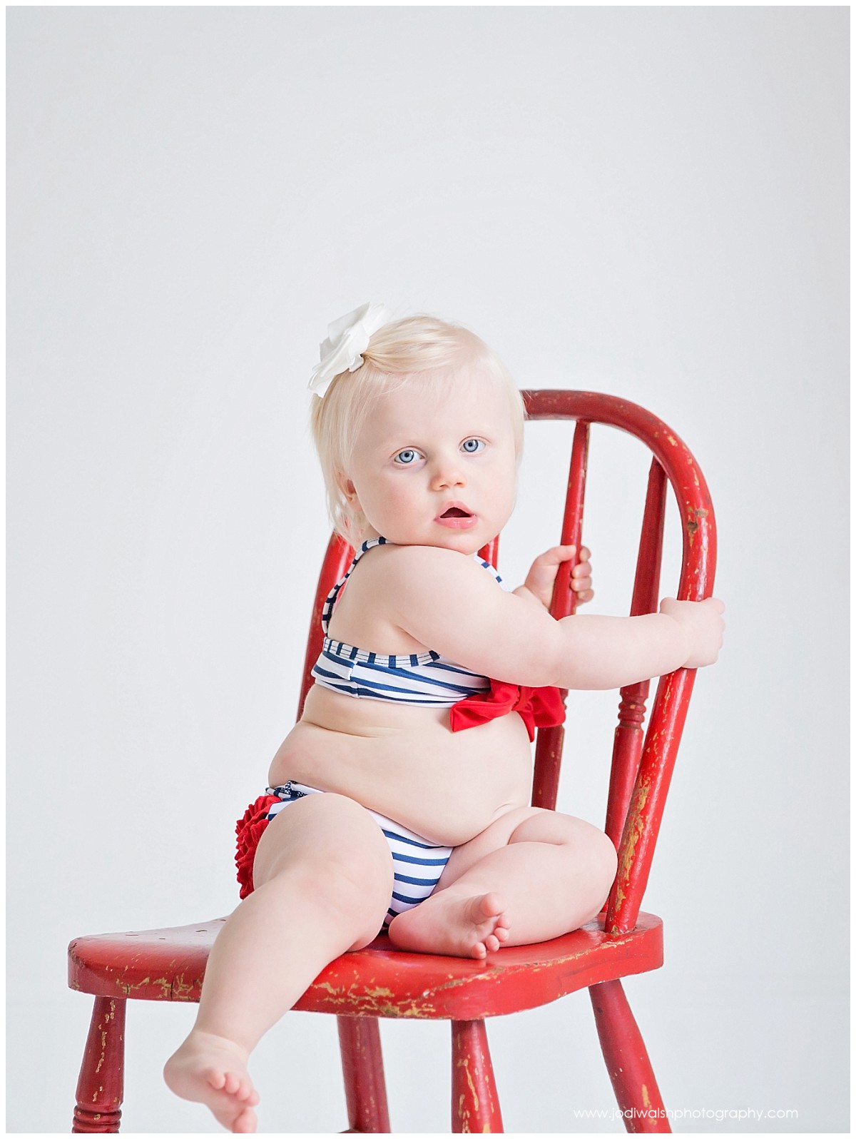 baby girl in red, white, and blue bikini on a red chair in Pittsburgh studio
