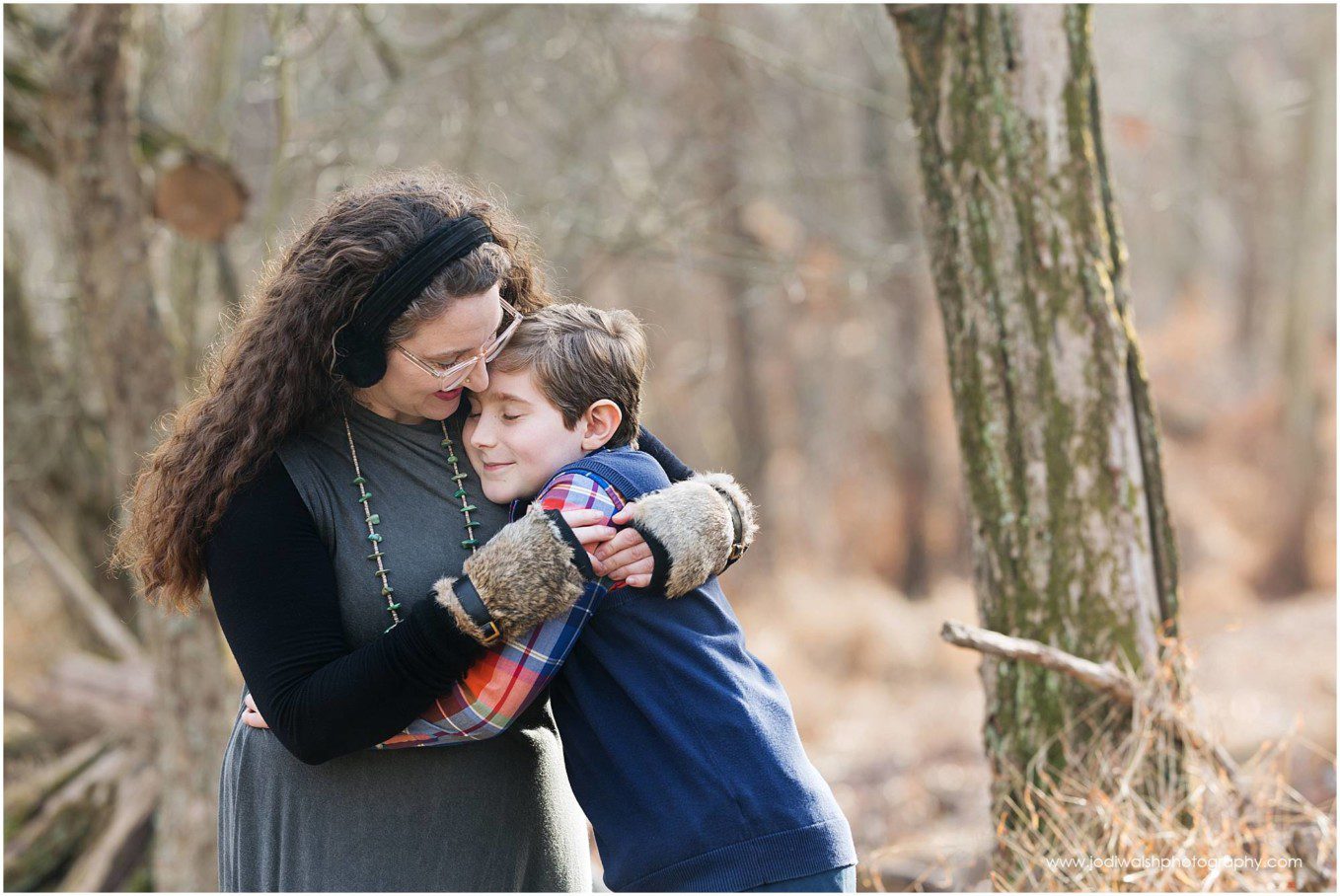 winter portrait of mother hugging son in the woods