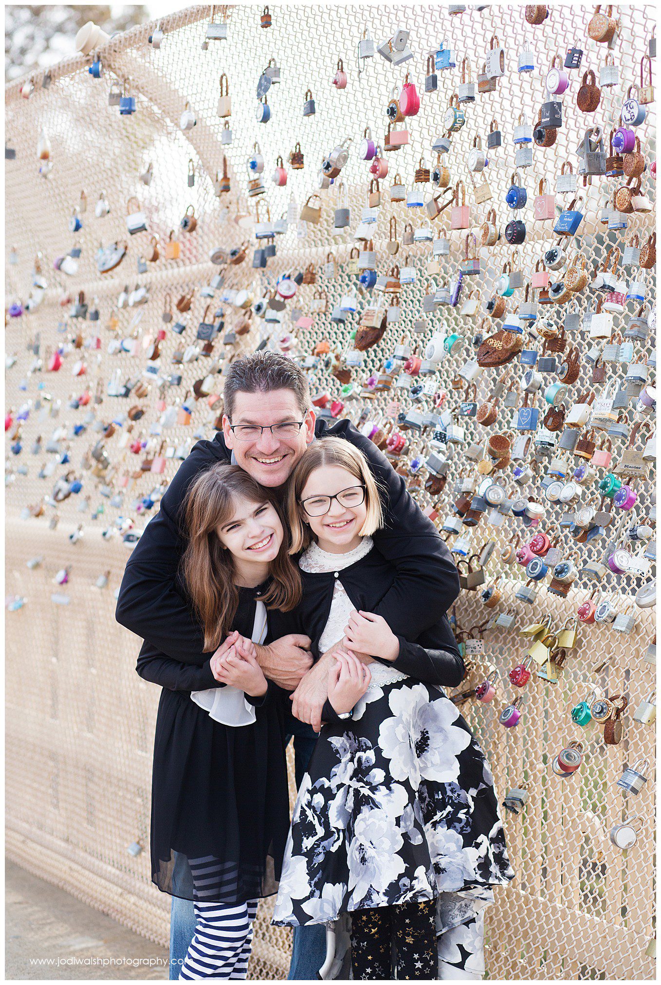 dad hugging daughters on Pittsburgh bridge with locks