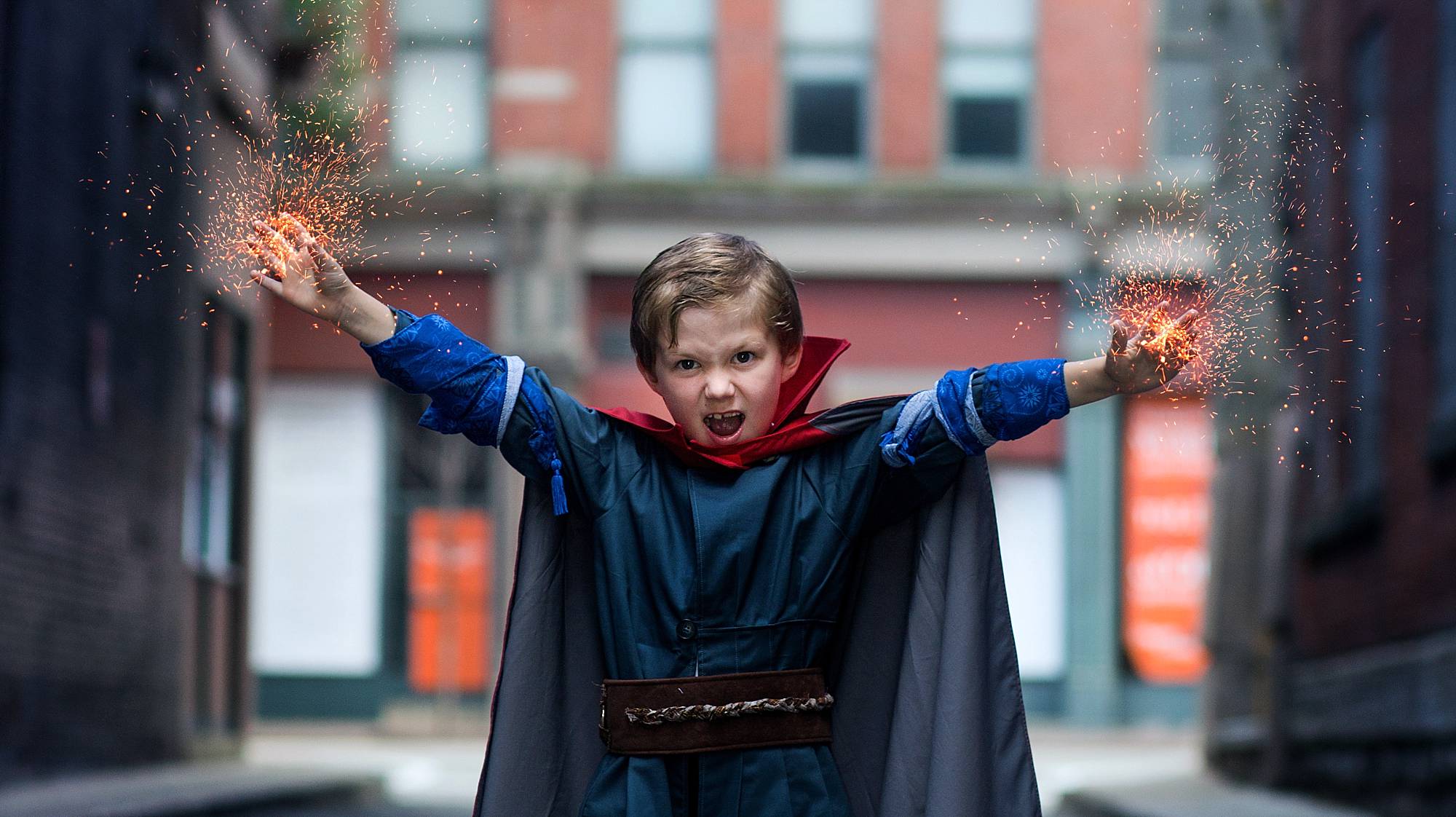 image of a little boy dressed as a comic book hero shooting orange sparks out of his hands