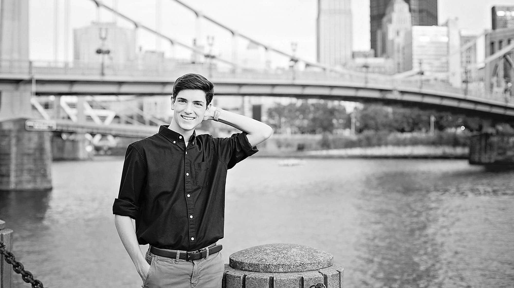 black and white image of a senior guy along the North Shore with the Andy Warhol Bridge behind