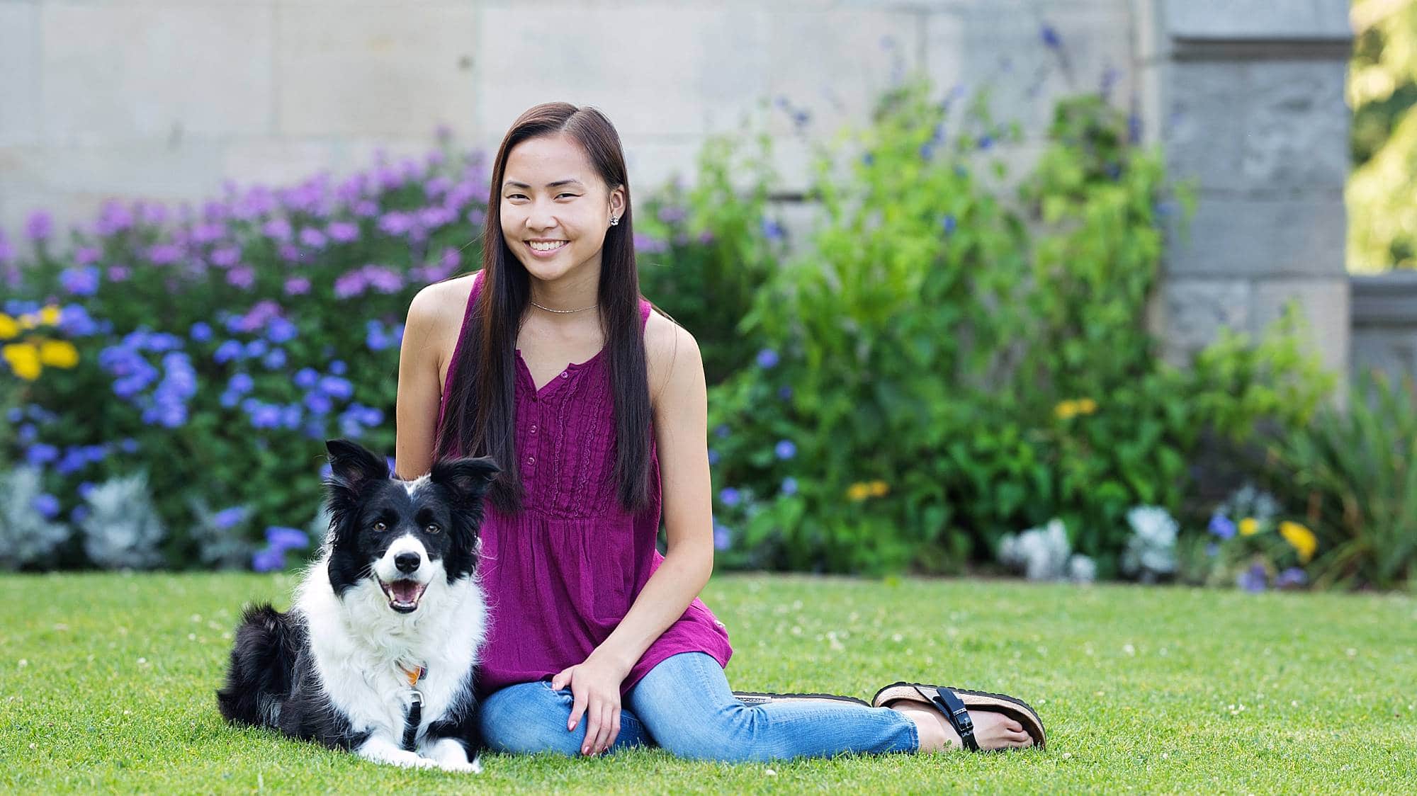 image of a senior girl sitting with her black and white shepherd dog in a garden