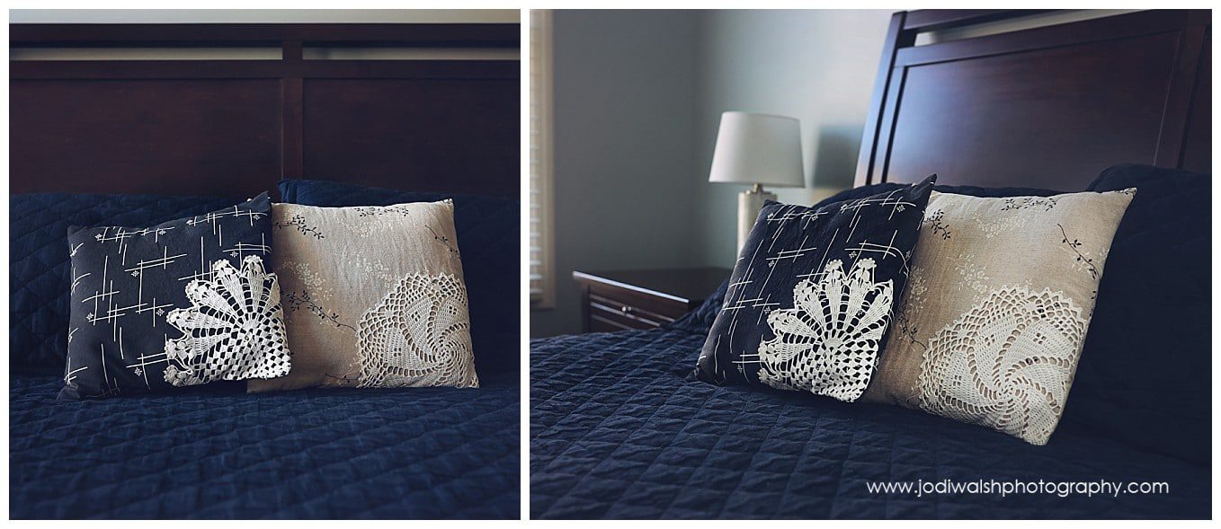 image of bed with two square pillows, gray and beige, on a navy blue quilt with a dark wood headboard