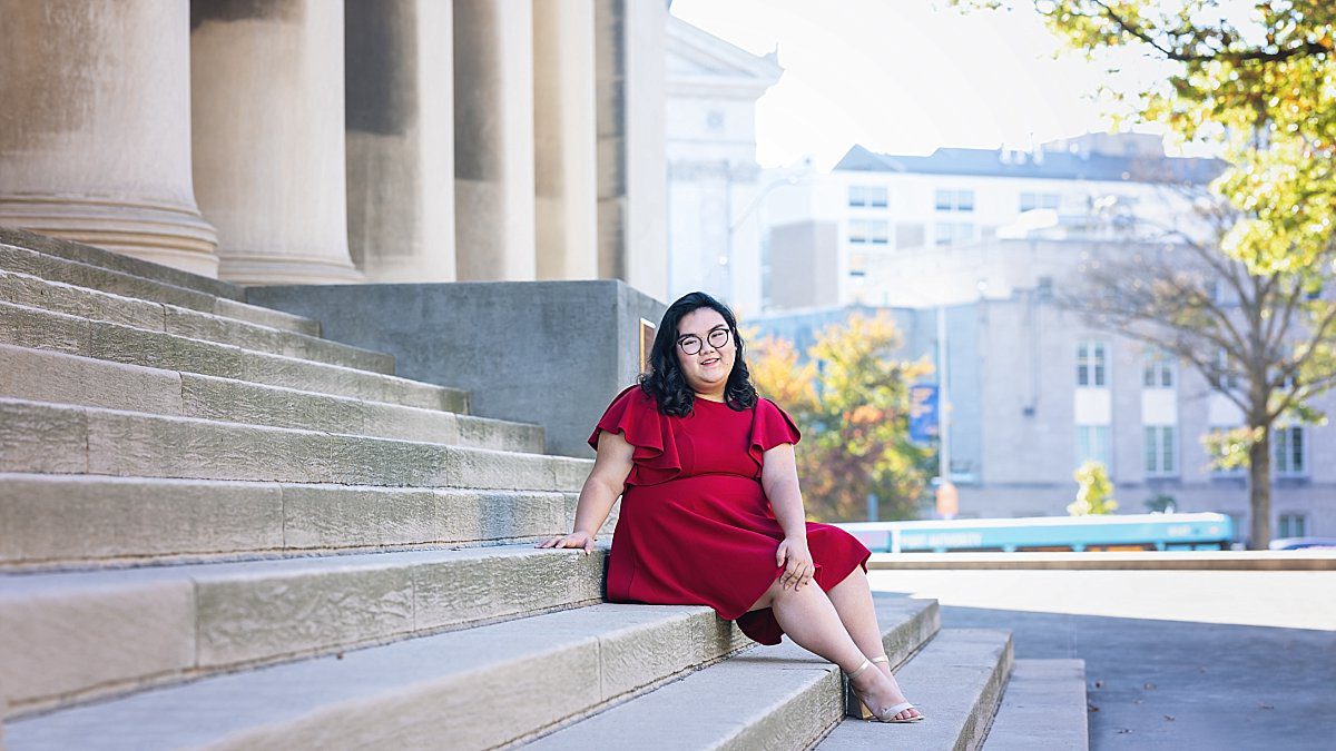 image of a senior girl wearing a red dress, sitting on the steps of Mellon Institute, Pittsburgh
