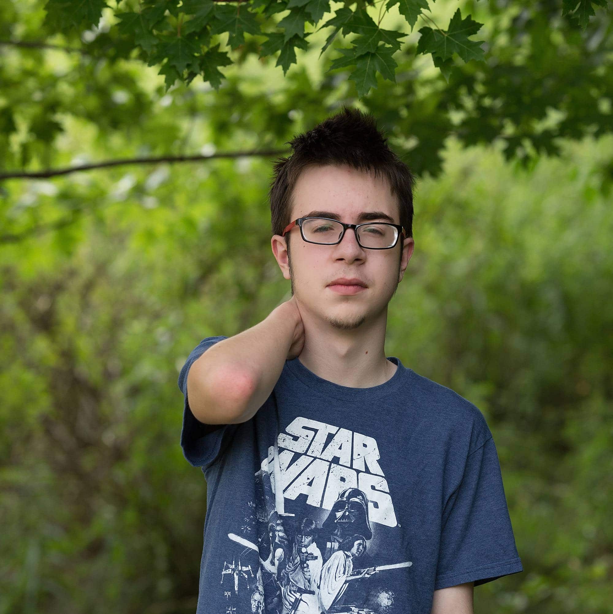 image of a teenage boy standing in the woods, wearing a Star Wars t-shirt