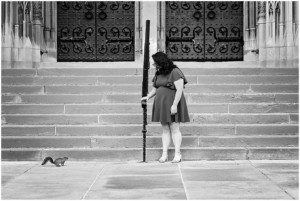 black and white image of a senior girl standing at the bottom of the steps of Heinz Chapel. She's looking down at a squirrel that is watching her.