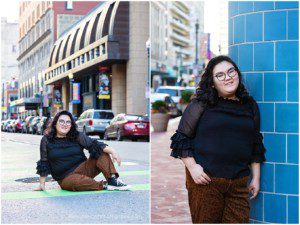 images of a senior girl on Penn Ave. Pittsburgh. She has dark wavy hair and glasses and is wearing a black blouse and animal print pants