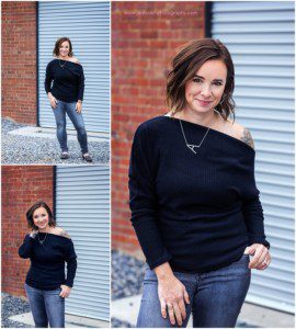 images of Amanda Brisco Photography. A woman with short dark hair wearing a black top, off the shoulder and jeans. She's standing in front of a brick garage.