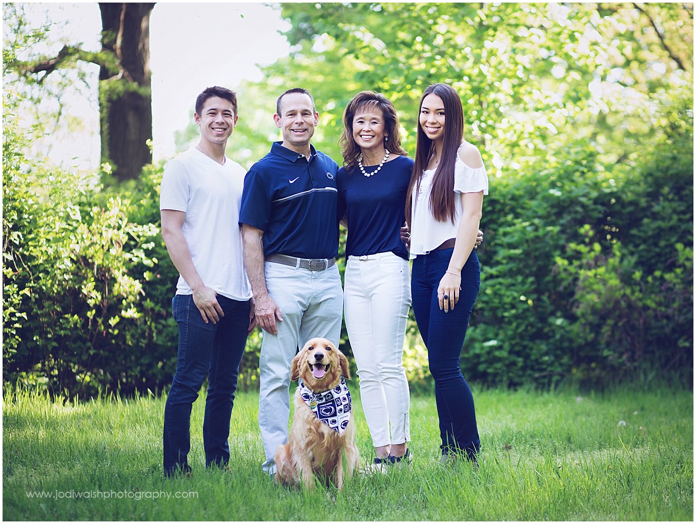 image of a family (mom, dad, adult children) and their dog in a grassy clearing at Point State Park in Pittsburgh.