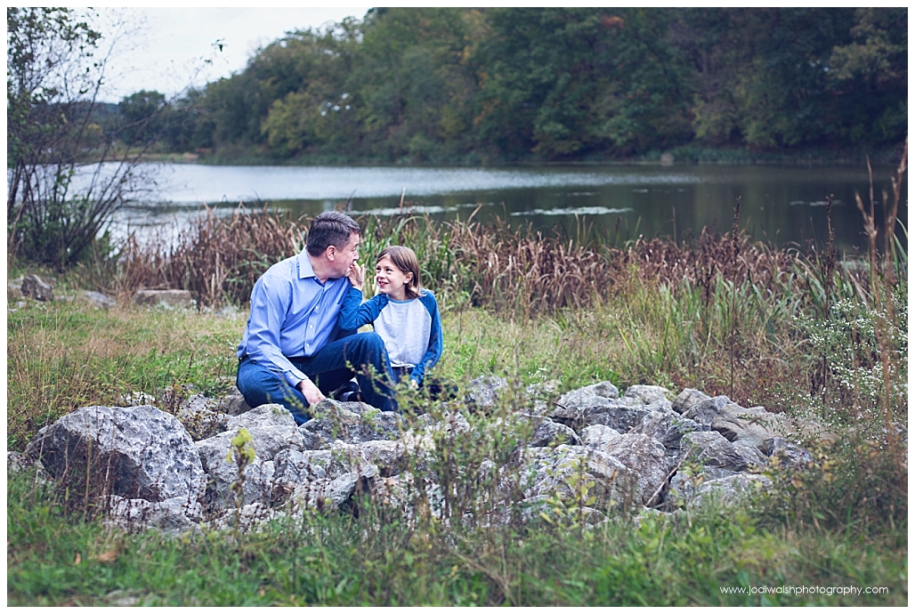 image of a dad and his young son. They're sitting on rocks near a lake in North Park.
