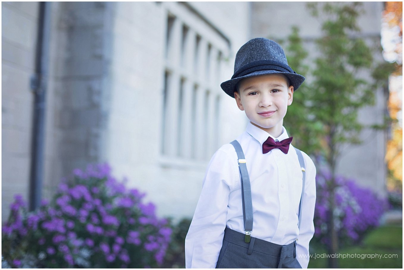 image of a little boy wearing a dark gray hat, red bow tie and suspenders near the mansion at Hartwood Acres, Pittsburgh