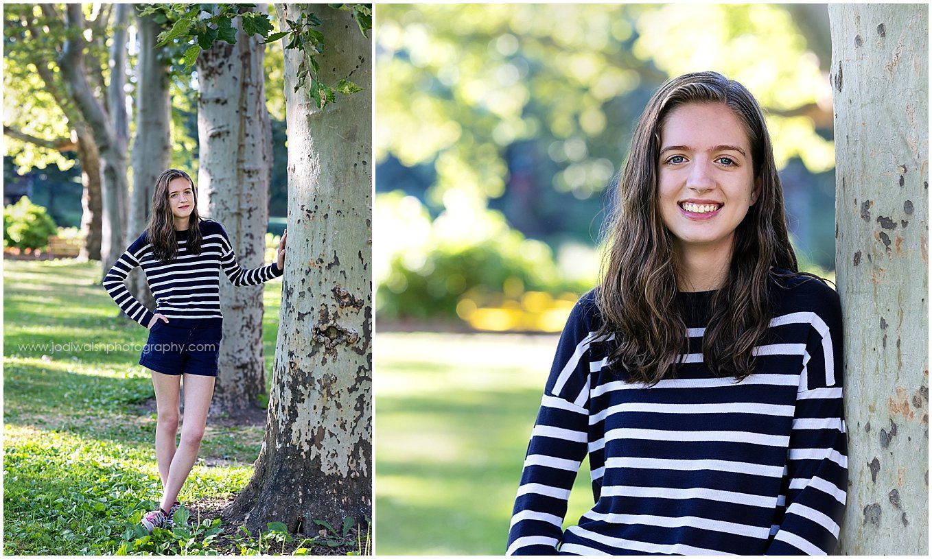images of a senior girl in a small park lined with trees.  She's wearing a striped long sleeve shirt and navy shorts.