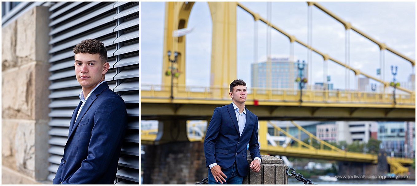 images of a senior guy with a navy blue suit jacket. He's standing along the North Shore trail in Pittsburgh with the Warhol Bridge in the background.