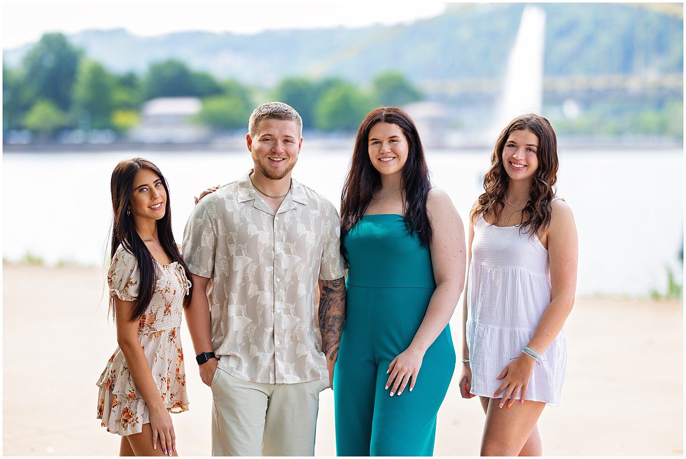 image of a family's four adult children on the North Shore in Pittsburgh. The Point State Park Fountain is visible in the background.