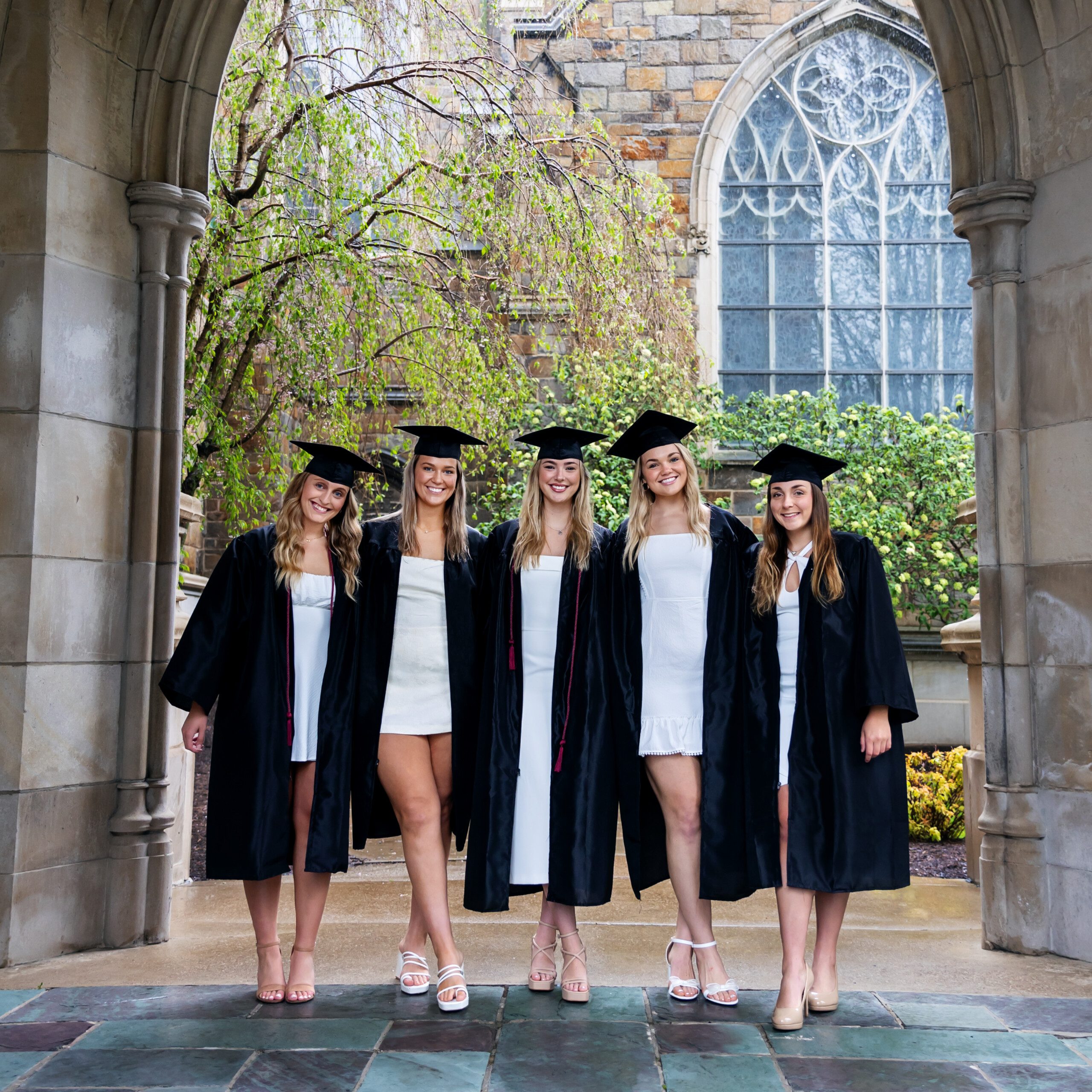 Gannon University graduates standing in white dresses and black robes in Erie
